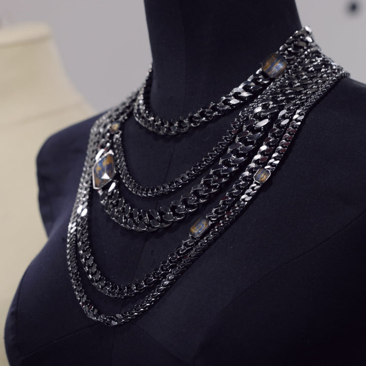 Collier plastron Nébula composé de chaine ruthénium et orné de strass bleus et dorés, posé sur un stockman noir